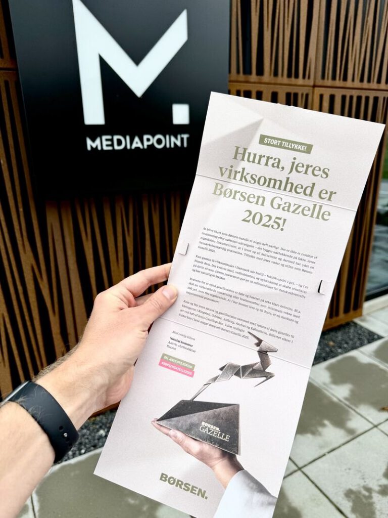Brevet fra Børsen om Gazelle 2025 holdt op foran MEDIAPOINTs skilt