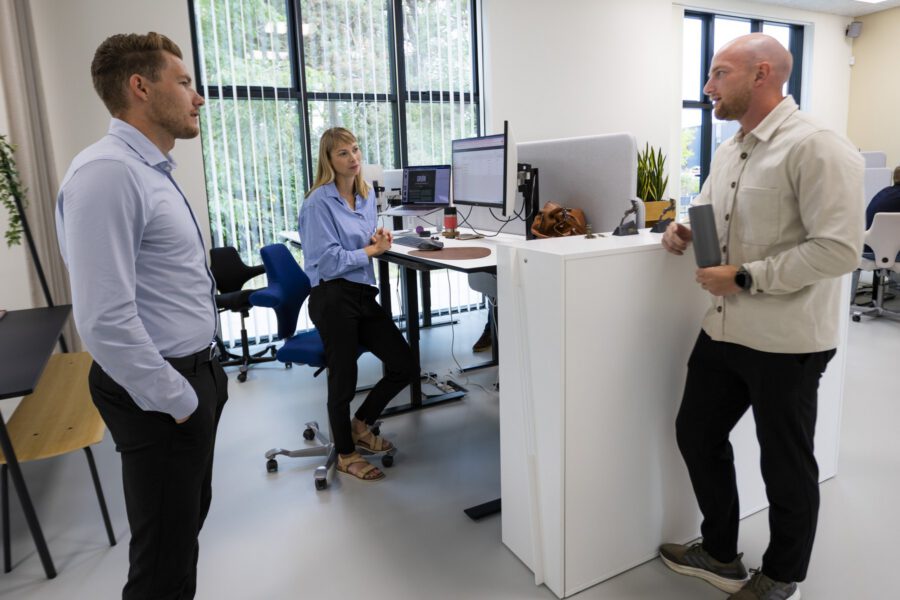 Tre kollegaer taler sammen ved skrivebordene i kontorlandskabet hos MEDIAPOINT